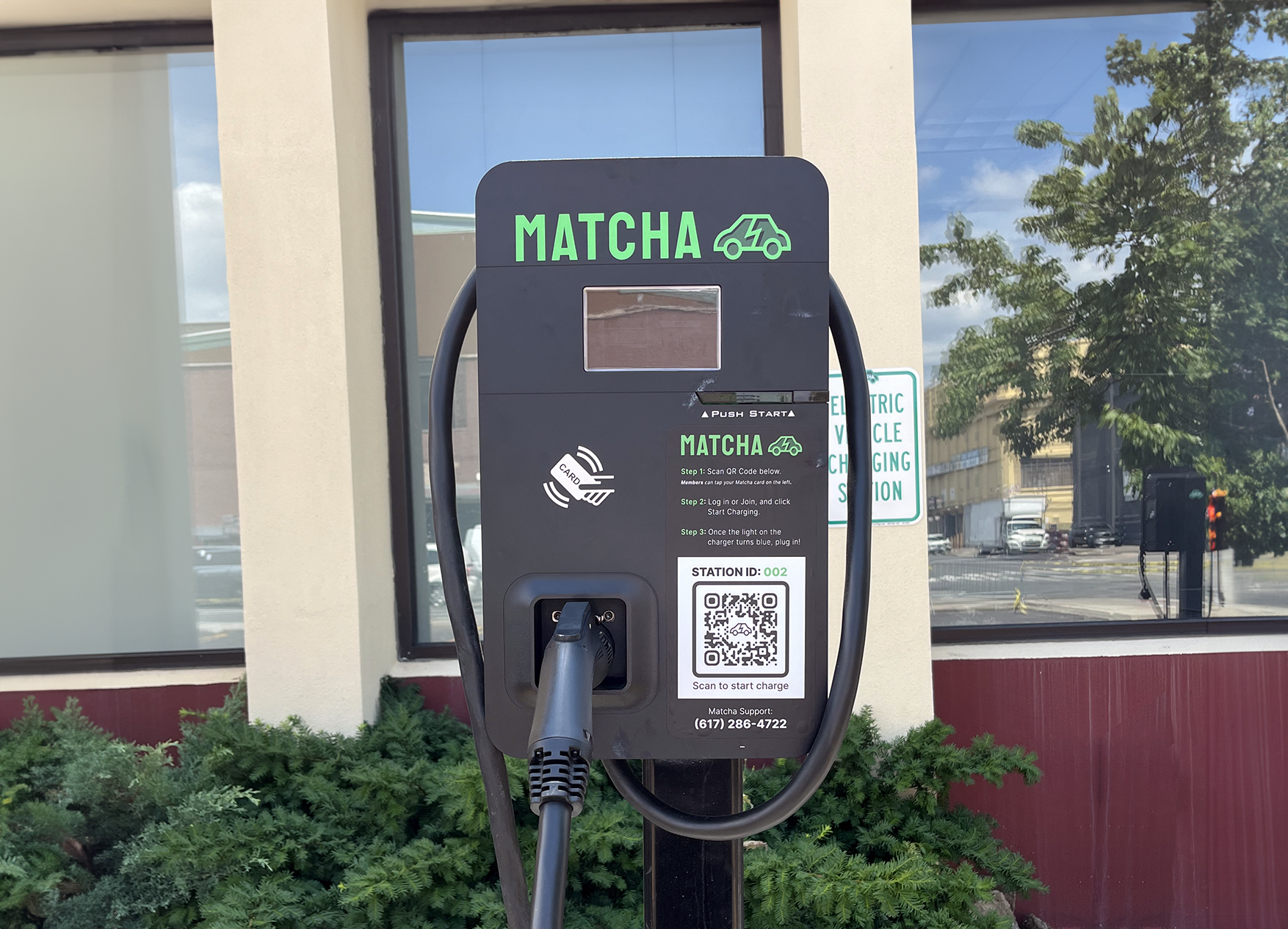 Matcha Electric vehicle charging station with a QR code for starting a charge, and a plugged-in charging cable, outside of the Brooklyn Army Terminal.